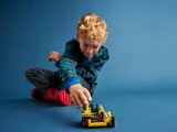 Boy playing with LEGO Technic 42163 bulldozer.