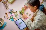 Child building LEGO set using digital instructions on a tablet.