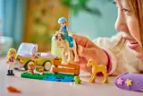 Child arranging LEGO Friends minifigures, horse, and picnic scene.
