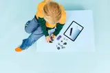 Child building LEGO hot rod with tablet.