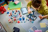 Child building LEGO Ferris Wheel with tablet.