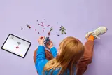 Child building a LEGO drone using a tablet for instructions.