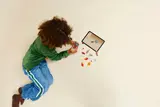 Child building LEGO with tablet.
