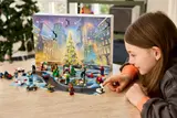 Child places LEGO piece on calendar playmat.