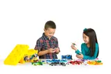 Two children building LEGO on table.