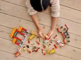 Hands assembling LEGO 80104 on floor.