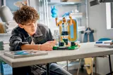 Boy looking at LEGO Messi figure.