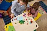 Adult and child building LEGO set.