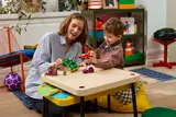 Adult and child playing with LEGO Marvel set.
