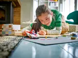 Girl playing with Shy Guy kart on floor.