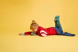 Child playing on floor with Yoshi bike.