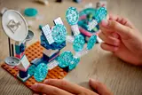 Hands assembling LEGO energy beam with clear elements.