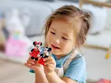 Child holding Mickey & Minnie figures.