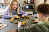 Two children playing with Technic models and cards.