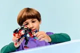 Child playing with mech and minifigure.