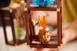 Holding orange crystal in stand.