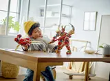 Child playing with the mech and flyer on a table.