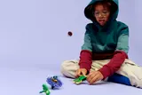 Child watching blue LEGO spinner.
