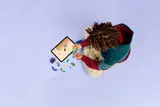 Child building LEGO with tablet.
