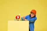 Child playing with Toad's house and Mario.