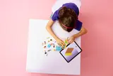 Child building LEGO van with tablet.