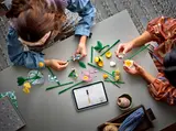 Two people building LEGO flowers.