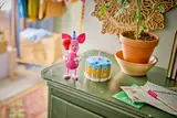 Piglet and cake displayed on a dresser.