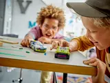 Two boys playing with the LEGO police and muscle cars on a table.