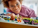 Child's hand moving the police car, with minifigures and muscle car in foreground.