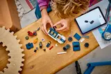 Child building LEGO Police Van with tablet.