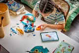 Child building LEGO carp set.