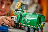 Child's hand on recycling truck's hopper, close-up.