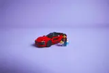 Red LEGO sports car and minifigure Kai on purple background.