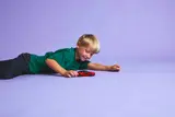 Child playing with the red LEGO sports car on a purple floor.