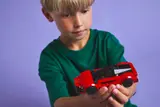 Child holding the red LEGO sports car.