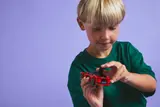 Child opening the trunk of the red LEGO sports car.