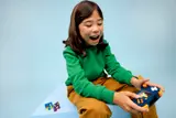 Child's joyful expression playing LEGO console.