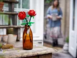 LEGO roses in vase on rustic table.