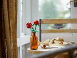LEGO roses in vase by sunlit window.