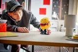 Builder admiring LEGO helmet on desk.