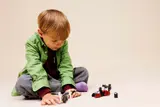 Child playing with LEGO Star Wars set on floor.