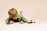 Child playing with LEGO Star Wars on floor.