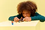 Child playing with LEGO figures on table.