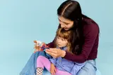 Adult guiding child in examining LEGO Spidey motorcycle.