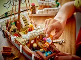 Hands placing Nami minifigure on LEGO Going Merry deck, interior visible.