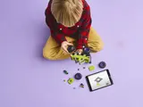 Child building LEGO with a tablet.