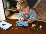 Child building LEGO ship with tablet.