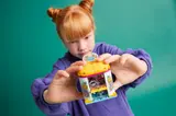 Child holding closed LEGO Friends accessory store.