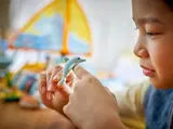 Child's hand holding a LEGO dolphin.