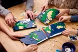 Hands building LEGO map sections.